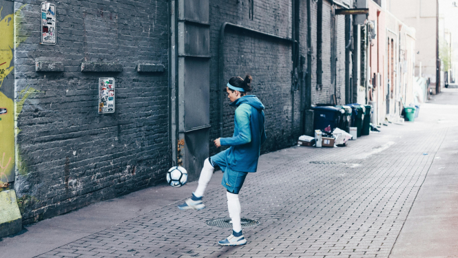 Meitene spārda futbola bumbu uz ielas