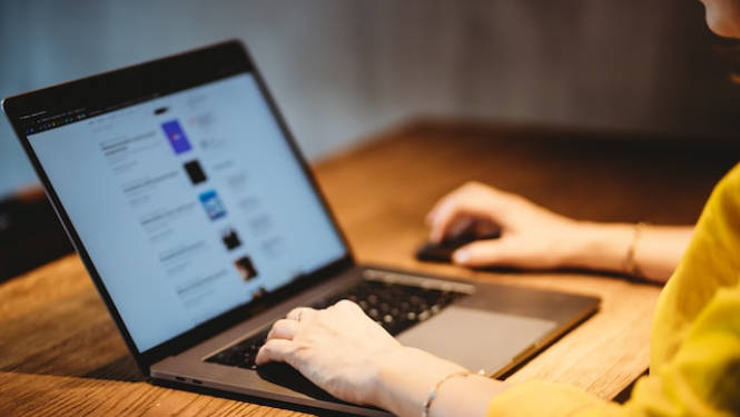 Laptops uz galda, redzmas cilvēka rokas