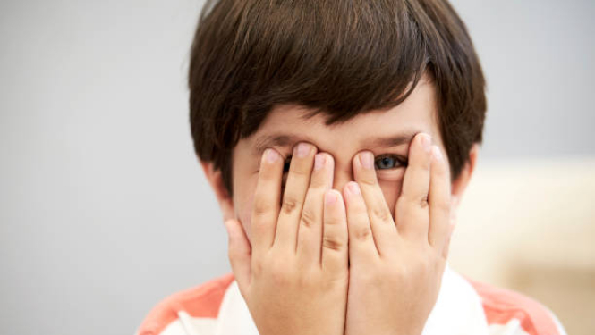 zēns ar rokām aizsedzis acis