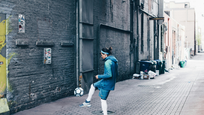 Meitene spārda futbola bumbu uz ielas