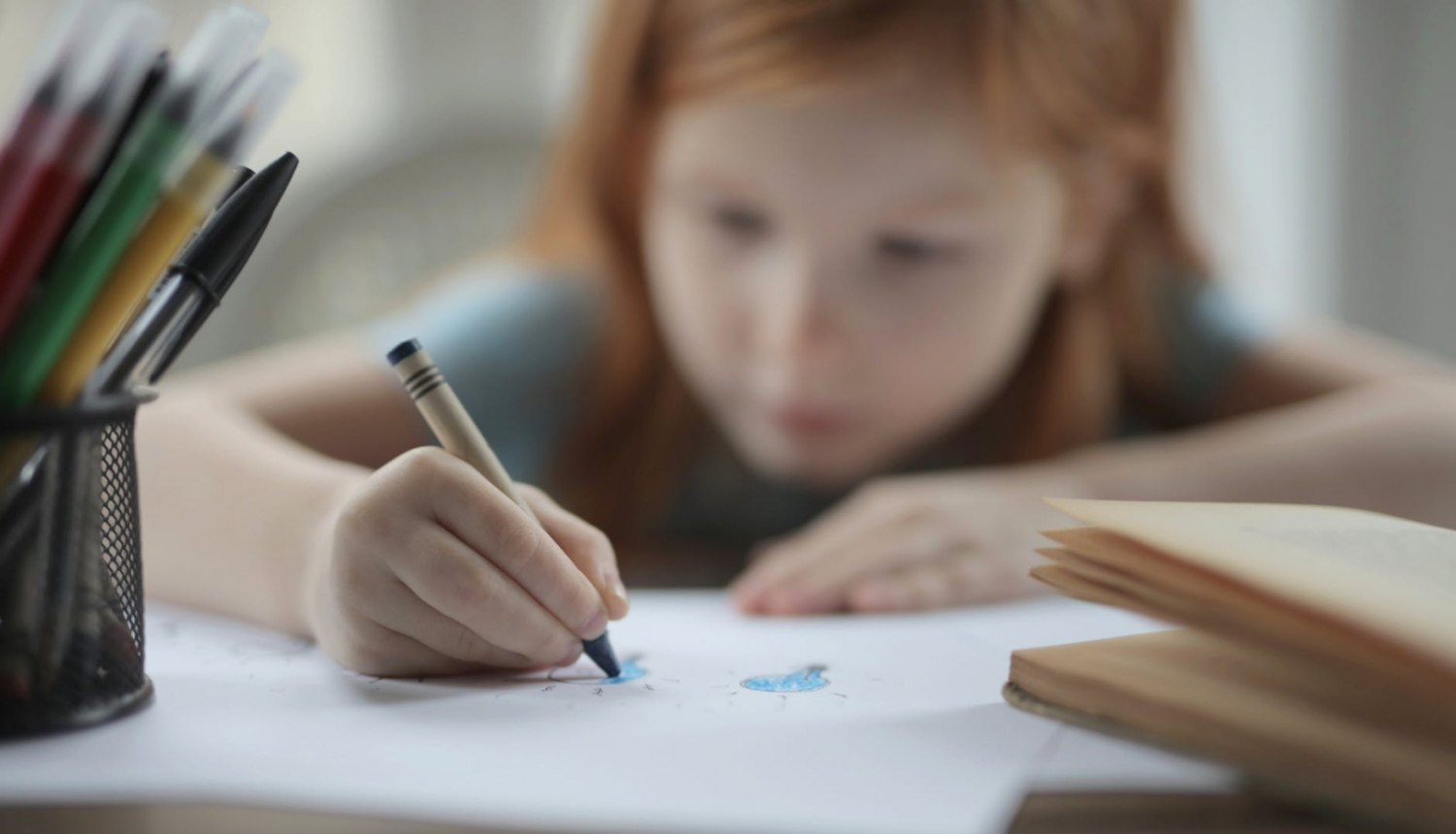 bērns zīmē uz lapas